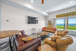 A modern living room with a sofa, armchairs, a coffee table, and a TV mounted on the wall.