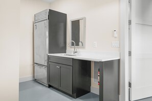 A compact kitchen with a built-in refrigerator, a sink, and a mirror above it.