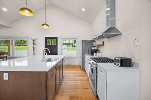 A modern kitchen with a large island, stainless steel appliances, and pendant lighting.
