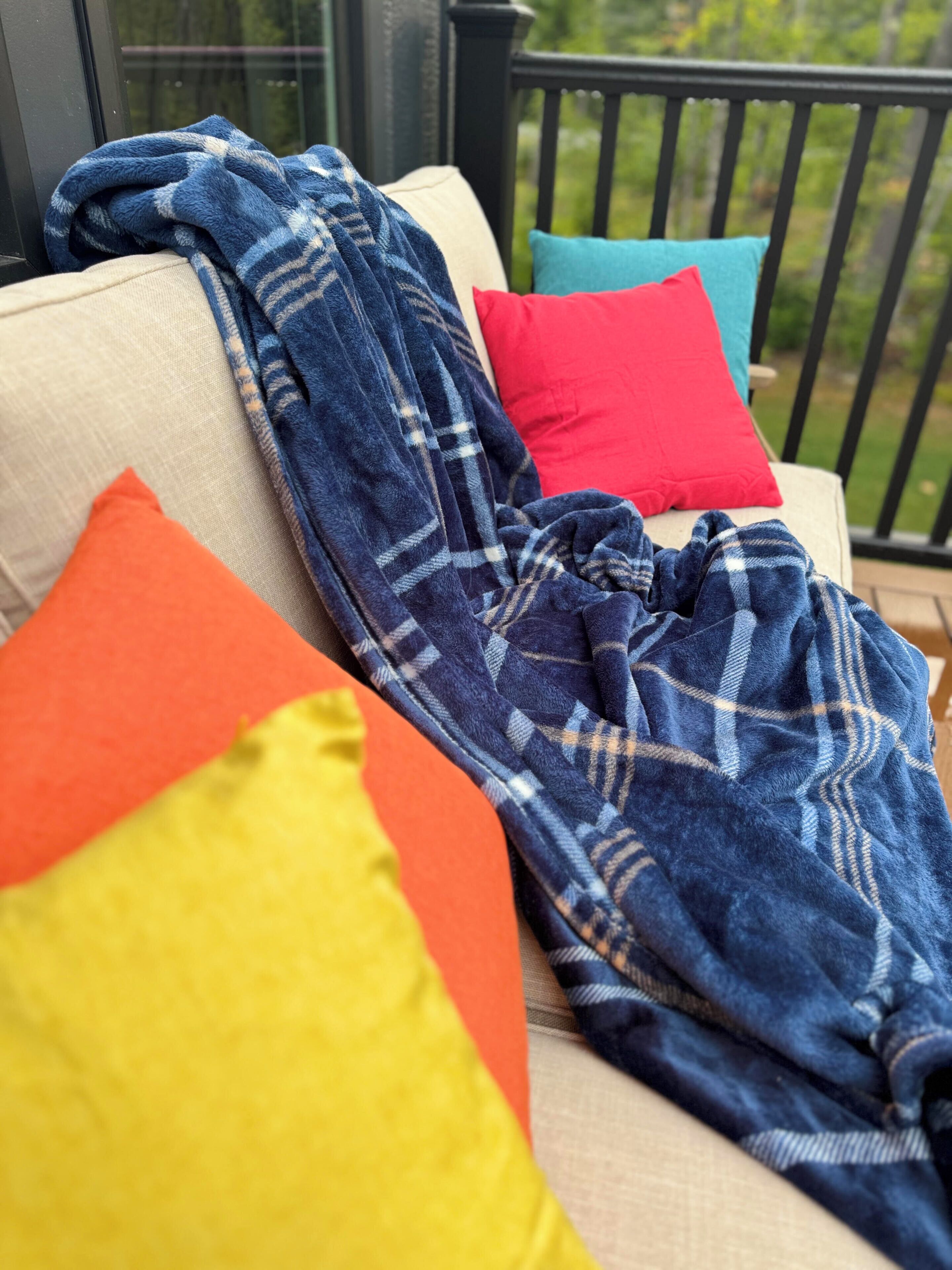 A sofa with a blanket and colorful pillows.