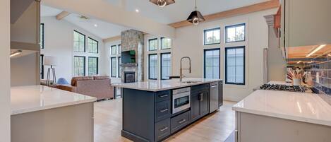 A spacious kitchen with a central island, large windows, and a stone fireplace.