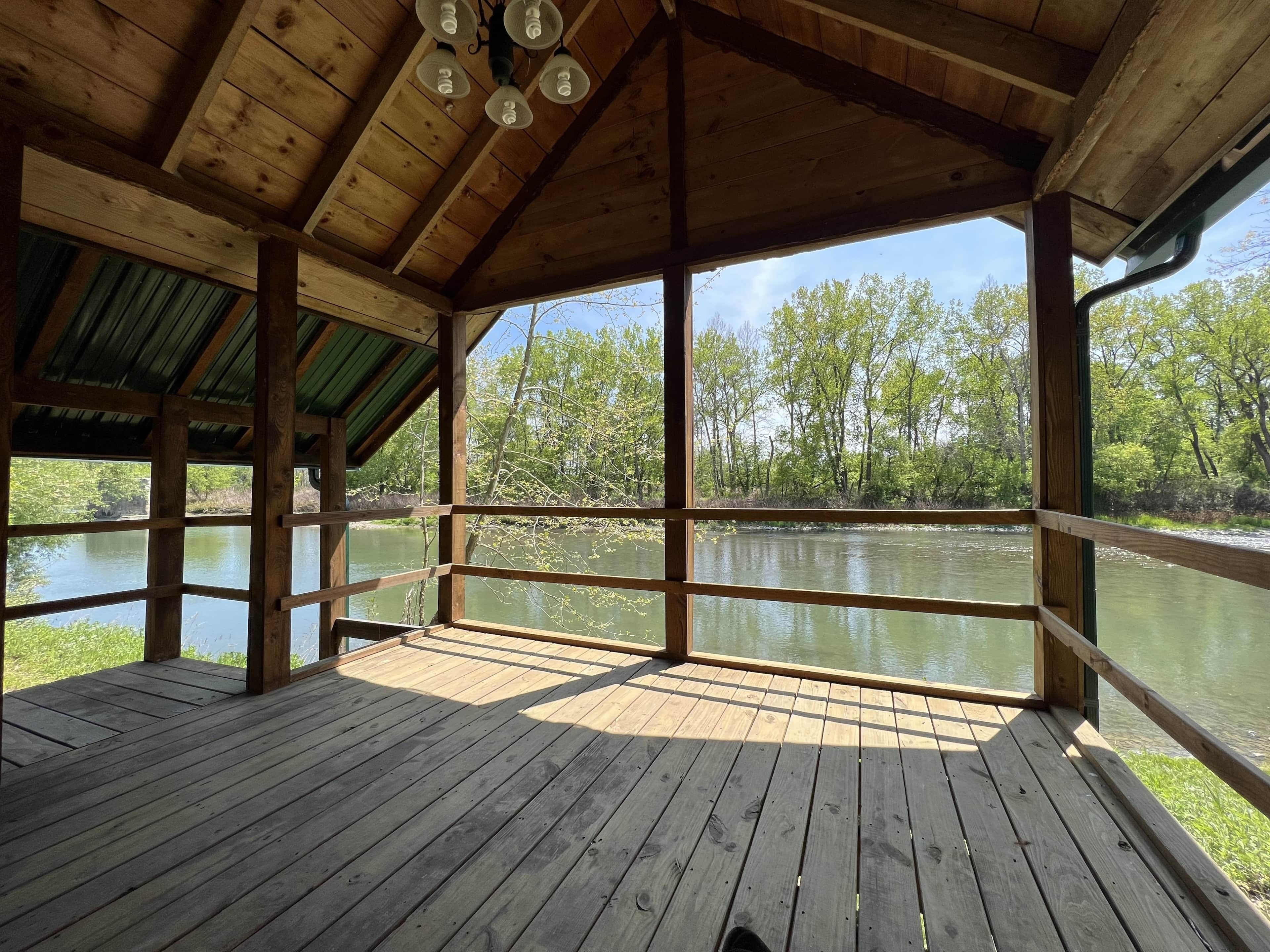 Eine Holzterrasse mit Blick auf einen Fluss und Bäume.