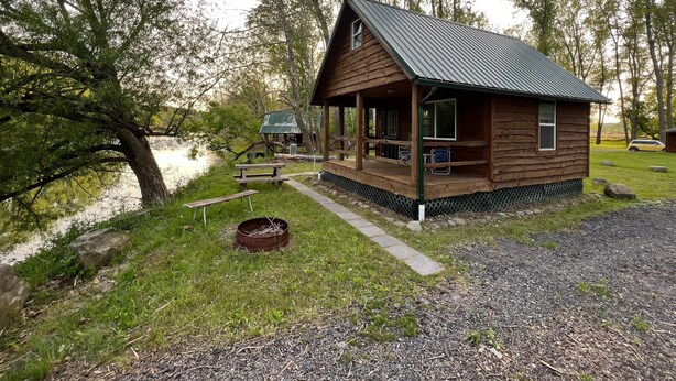 A wooden cabin with a porch, a picnic table, and a small shed by a body of water. - :)River Getaway LogCabin | 4ComfyQBed +Electric #3 (Belfast)