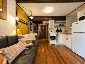 Ein gemütliches Wohnzimmer mit einer Ledersofa, einem Essbereich und einer Küche mit weißen Geräten.