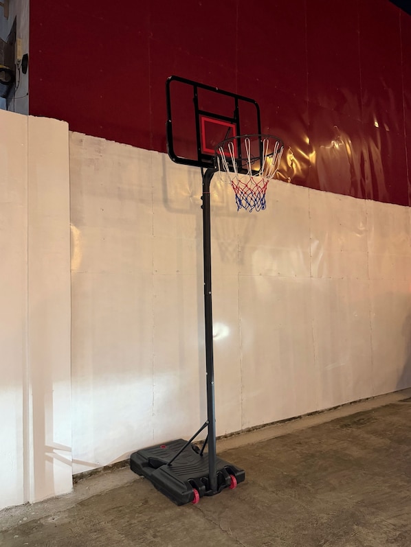 A basketball hoop with a net, mounted on a wall with a red background.