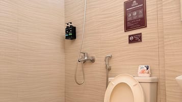 Une salle de bain équipée de toilettes, d’une douche et d’un bidet. On y trouve des articles de toilette accrochés au mur, ainsi qu’un panneau indiquant que cette salle de bain est réservée aux invités.
