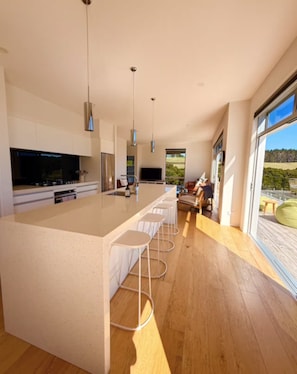 A modern kitchen with a large island, bar stools, and a view of the outdoors.