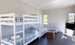 A room with bunk beds, a sofa, a television, and a small table.