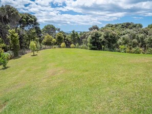 A grassy field with trees and a clear sky.