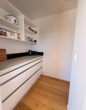 A kitchen with white cabinets, a black countertop, and a wooden floor.