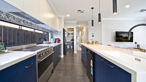 A modern kitchen with a central island, built-in appliances, and pendant lighting. - Serenity Place - Relax, Unwind & Explore at Serenity Place (Mannering Park)