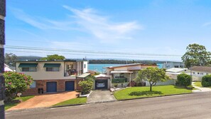 A residential area with houses, a clear sky, and a body of water in the background. - Serenity Place - Relax, Unwind & Explore at Serenity Place (Mannering Park)