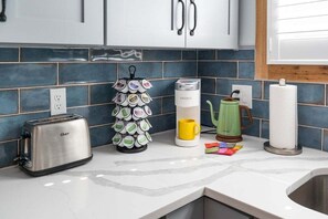 A kitchen with a toaster, a coffee maker, a mug, and a mug holder with tea bags. - Cottage, Putting Green, Firepit, Walk to DT (St. Augustine)