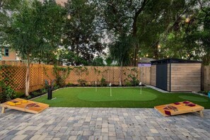 A backyard with a wooden deck, a small shed, and a lawn. - Cottage, Putting Green, Firepit, Walk to DT (St. Augustine)