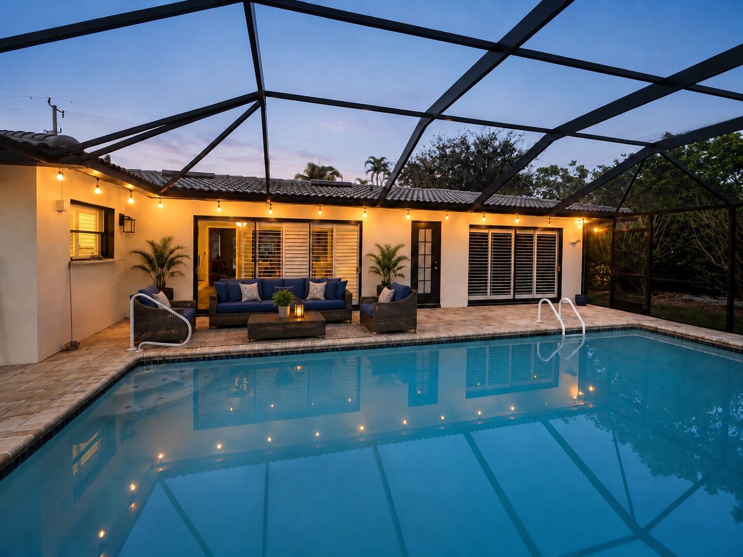 A swimming pool with a covered patio area, outdoor furniture, and a view of the surrounding landscape.