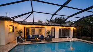 Una piscina con un porche techado, mobiliario exterior y vistas del paisaje circundante.