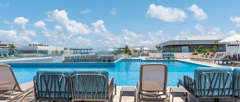 A rooftop pool area with lounge chairs and a clear view of the sky.