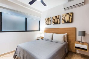 Ein Hotelzimmer mit Bett, Nachttisch, Wandairconditioner und abstrakten Wandbildern.