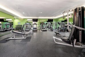 Ein Fitnessstudio mit Laufbändern, Crosstrainern und Gewichtecken.