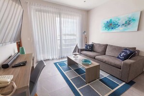 A modern living room with a sofa, coffee table, and a painting on the wall. - Rooftop Pool Condo 150m from 5th Avenue (Playa del Carmen)
