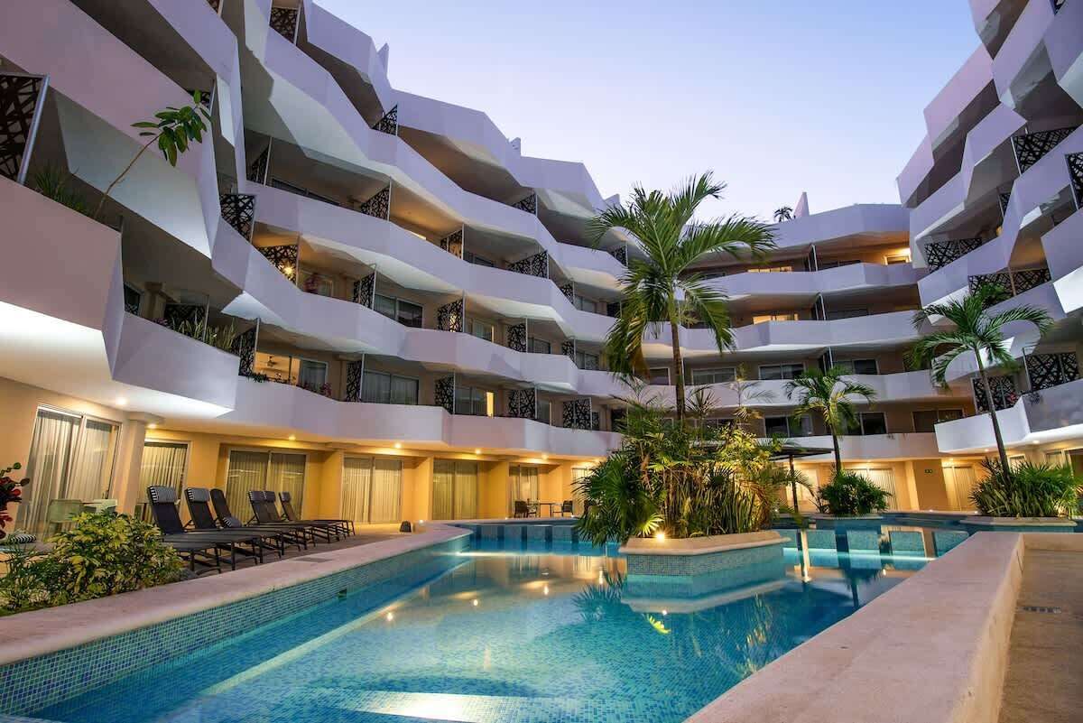 Un hôtel à plusieurs étages doté d’une piscine, de balcons et d’un espace extérieur aménagé pour s’asseoir.
