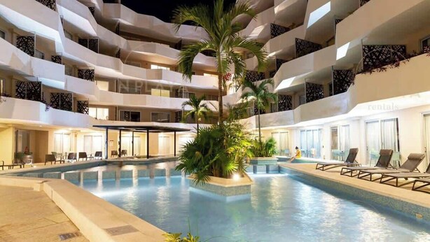 Ein mehrstöckiges Hotel mit einem zentralen Schwimmbad, Balkonen und Sitzbereichen im Innenbereich.