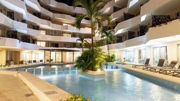 A multi-level hotel with a central swimming pool, balconies, and indoor seating areas.