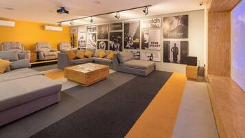 A modern lounge area with sofas, a coffee table, and a wall decorated with movie posters.