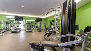 A gym with various exercise equipment, including treadmills and weight machines, in a room with green walls.
