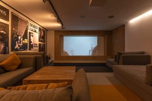 Un salon moderne doté d’un grand écran pour regarder des films, de sièges confortables et d’un mur décoré d’affiches de films.