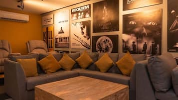 A modern living room with a sectional sofa, a wooden coffee table, and a wall adorned with movie posters.