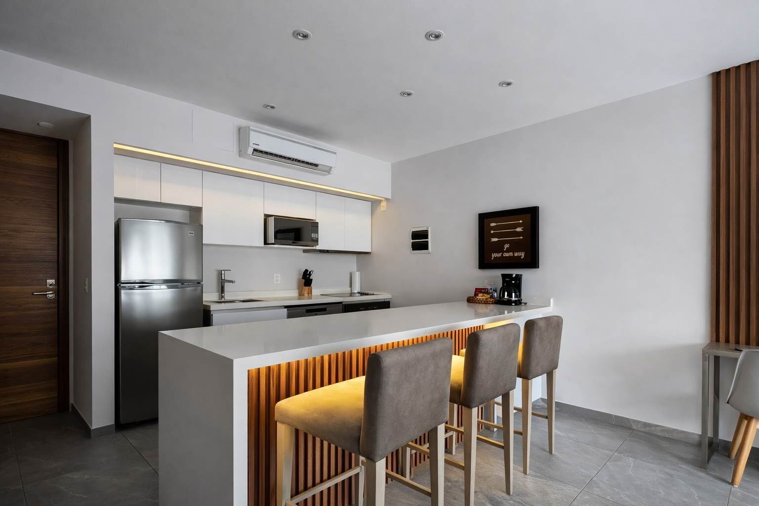 A modern kitchen with a central island, stainless steel appliances, and a wooden accent wall.