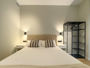 Een hotelkamer met een groot bed, twee nachtkastjes, een kledingkast en twee wandlampen.