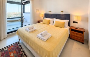 A hotel room with a large bed, two bedside tables, a view through a glass door, and a patterned rug. - Amazing apartment in Estepona with swimming pool (Estepona)
