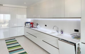 A modern kitchen with white cabinetry, a stainless steel sink, and a built-in dishwasher. - Amazing apartment in Estepona with swimming pool (Estepona)