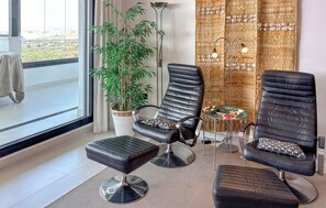 A modern room with two black leather chairs, a small round table, a tall floor lamp, and a large potted plant. - Amazing apartment in Estepona with swimming pool (Estepona)