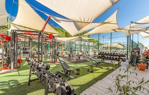 An outdoor gym with various exercise equipment, including weight benches, dumbbells, and a squat rack. - Amazing apartment in Estepona with swimming pool (Estepona)