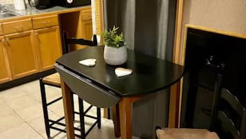 Una cocina compacta con una mesa de comedor, sillas, un refrigerador y una pequeña planta en maceta.