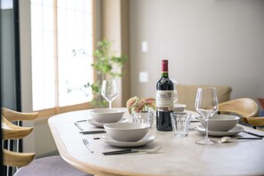 A dining table set with white bowls, wine glasses, and a bottle of wine. - Shinjuku 6-chome City Stay 1F (Shinjuku)