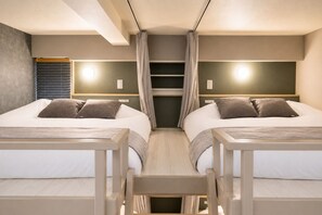 Habitación de hotel con dos camas, una mesita y una ventana con persianas.