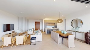 A modern living room with a flat-screen TV, a dining area with a wooden table, and a kitchen in the background. - Perched Above Paradise | Villa 1041 (Famagusta)