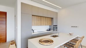 A modern kitchen with a central island, built-in appliances, and a minimalist design. - Perched Above Paradise | Villa 1041 (Famagusta)