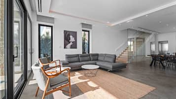 A modern living room with a sectional sofa, a round coffee table, and a dining area with chairs.