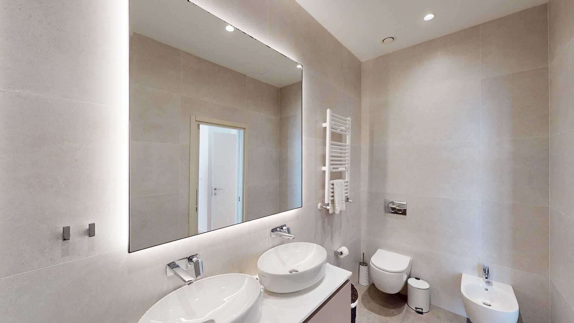 Un baño moderno con dos lavamanos, un inodoro y un bidé.