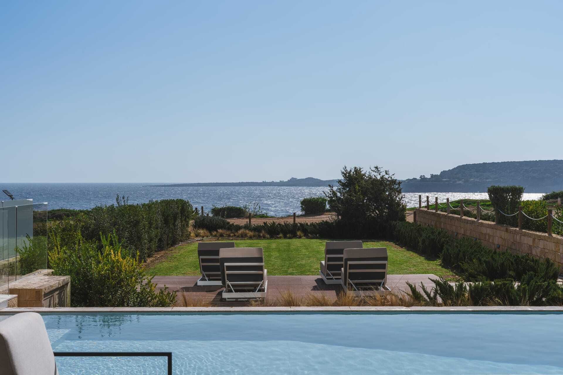 A swimming pool with lounge chairs and a view of the sea.