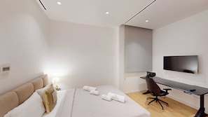 Habitació d'hotel amb un llit, una taula, una cadira, un televisor i una finestra.