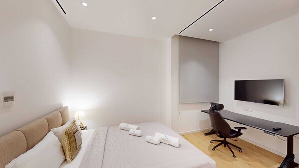 Une chambre d’hôtel avec un lit, un bureau, une chaise, une télévision et une fenêtre.