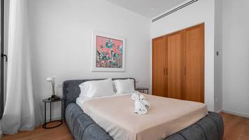 Ett sovrum med en säng, ett sängbord, en nattduksbord, en garderob och en tavla på väggen.