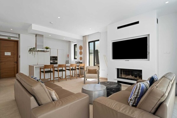 A modern living room with a sofa set, a dining area with chairs, a flat-screen TV mounted on the wall, and a fireplace. - Escape to Coastal Comfort | Villa 1030 (Famagusta)