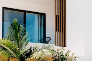 A modern building with a large window, a glass balustrade, and a vertical wooden panel. - Escape to Coastal Comfort | Villa 1030 (Famagusta)